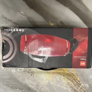 Rugby H9 Portable Wireless Speaker - Trådlös högtalare med 1800 mAh batteri, bärrem och flera färgalternativ. Kompatibel med mobiler, surfplattor och laptops. Lådan har mindre slitage men produkten är ny i förpackning. Perfekt för musik på språng och utomhusaktiviteter.