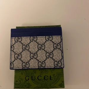 Beige plånbok med blåa G - Säljer en helt ny plånbok man får med låda på köpet