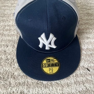 New Era Yankees keps blå/grå 59FIFTY - Snygg 59FIFTY keps från New Era med New York Yankees broderat framtill och på sidan. Kepsen är mörkblå framtill och har grå paneler med marinblå brodyr. Platt skärm och klassisk passform, perfekt för dig som gillar streetstyle och sport.