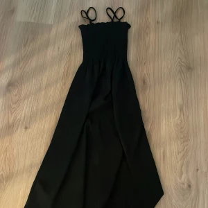 Svart långklänning med smock och smala axelband - Svart långklänning med smockad överdel och smala axelband. Väldigt töjbar så skulle säga att den passar S oxå. Knappt använd och skriv om ni har några frågor💕