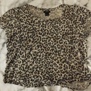 Leopardmönstrad topp från Lindex - Säljer en tunn och luftig T-shirt från Lindex i storlek M. Toppen har ett coolt leopardmönster i beige och svart, rund halsringning och korta ärmar. Perfekt för dig som vill sticka ut med ett djurmönstrat plagg.
