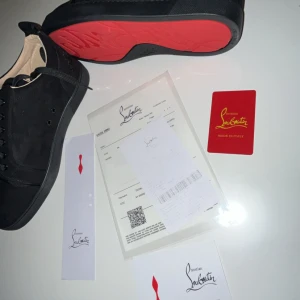 Christian Louboutin svarta sneakers - Svarta sneakers från Christian Louboutin med klassisk röd sula. Snygg, stilren design med rund tå och snörning. Yttermaterialet är mocka och insidan är ljusbeige. Perfekt för dig som vill ha en lyxig och modern look.