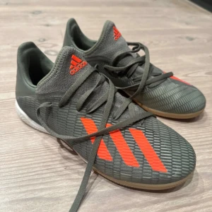 Adidas grå fotbollsskor med orange detaljer - Adidas inomhusfotboll skor. Har typ inte använt den. Kontakta för mer info