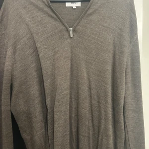Brun stickad tröja med half zip - Säljer en brun stickad tröja från Bläck med half zip-dragkedja vid halsen. I storlek L