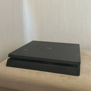 PlayStation 4 Slim med FIFA 22 och FIFA 21 - Sony PlayStation 4 Slim i svart, med synliga tecken på användning och några repor. Medföljer FIFA 22 (originalfodral) och FIFA 21 (skiva). Perfekt för dig som vill spela populära fotbollsspel på en pålitlig konsol. Du får även med HDMI kabel kontrol finns ej men jag säljer för ett bra pris så du har gott om pengar till en kontroll 