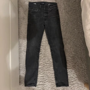 Svarta slim straight jeans Jack & Jones - Snygga svarta jeans från Jack & Jones i modellen Slim Straight Tim. Jeansen har klassisk femficksdesign, raka ben och en smal passform. Tillverkade i stretchigt jeanstyg för extra komfort. Perfekta för dig som gillar en stilren look.