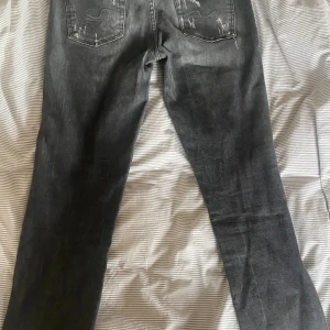 Svarta jeans 7 Jeans med slitningar  - Säljer ett par svarta 7 Jeans. Passar Slim/Skinny i W28 och L29. Jeansen är i mycket gott skick och har unika slitningar.