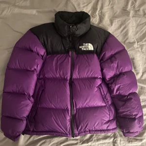 Lila The North Face 700 dunjacka - Säljer en ikonisk The North Face 700 dunjacka i lila och svart. Jackan har hög krage, dragkedja framtill och två sidofickor. Perfekt för kalla dagar och den är riktigt snygg. Jättebra skick, har inga skador eller märken då jag knappast använt den :)