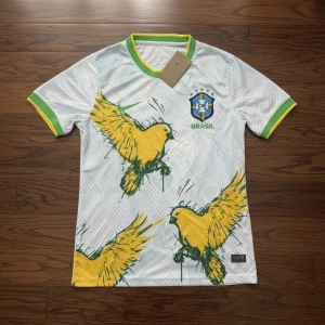Vit Brasilien fotbollströja Nike - Snygg vit Brasilien fotbollströja från Nike med stora gula fåglar tryckta på framsidan. Tröjan har gröna och gula detaljer vid krage och ärmslut samt Brasilien-emblem på bröstet. Tillverkad i lätt och ventilerande material, perfekt för match eller träning.