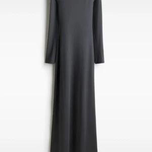 Svart långklänning med öppen rygg - Supersnygg svart långklänning med lång ärm och en djup, öppen rygg. Klänningen har en stilren och enkel design med figurnära passform och mjukt, stretchigt material som känns skönt mot huden. Perfekt för dig som gillar minimalistisk stil med en twist.