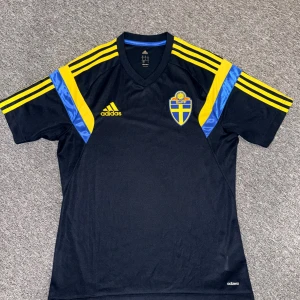 Svenska landslaget fotbollströja Adidas M - Säljer en svart fotbollströja från Adidas med Sveriges landslagsemblem på bröstet. 2014-15 tränings tröja i storlek M. Nästan aldrig andvände den på grund av att en är för stor. Hör av dig vid frågor eller behov av fler bilder!😊