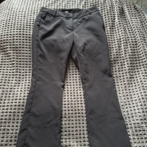 Svarta bootcut kostymbyxor BikBok - Svarta kostymbyxor från BikBok i storlek 38. Byxorna har bootcut-modell med klassiska fickor fram och bak, hällor för bälte och stängs med dragkedja och knapp. Perfekta för en clean och stilren look.