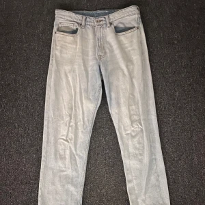 Ljusblå Valient raka jeans - Snygga ljusblå jeans med klassisk femficksdesign och raka ben. Jeansen har bälteshällor, knapp och dragkedja framtill samt två bakfickor. Materialet är jeans och färgen är ljusgrå, perfekt för en chill och stilren look. Med storleken S. Tyvärr en liten fläck på ett av benen.