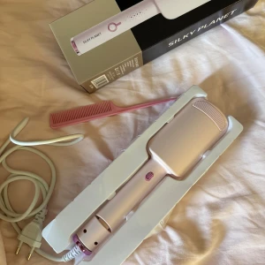 Silky Planet Vågstyler - Silky Planet vågstyler i ljusrosa, perfekt för att skapa enkla vågor och lockar. Användarvänlig design med LED-display och flera stylinglägen. Produkten är i mycket fint skick och levereras med originalkartong och kam. Den är bara använt 1 g 