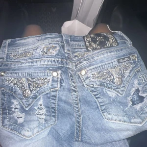 Miss Me ljusblå lågmidjade jeans - Säljer ett par ljusblå Miss Me jeans med låg midja och slim boot i modell. Skulle säga som bootcut fast det börjar längre ner.. Jeansen har snygga detaljer med bling. Använts ungefär 4 gånger och är så så bra skick!. Nypris 1339 säljer för 1000. Pris går att diskuteras men eftersom de är så nya helst inte.🩷🫶 