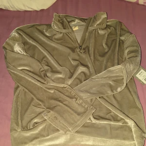 Beige velourtröja med half zip från UNIQ - Säljer en beige långärmad tröja i mjuk och glansig velour från UNIQ. Tröjan har en snygg half zip med ringdetalj i dragkedjan och en avslappnad passform. Perfekt för dig som gillar en chill och trendig stil.