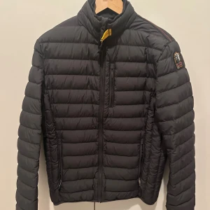 Parajumper durjacka GRÅ - 🧥 Parajumpers Anchorage Snygg och lätt dunjacka i mörkgrått/svart. Klassisk modell med gul rem och logga på ärmen. Väldigt bra skick – fräsch, inga skador eller fläckar. Perfekt för höst/vinter 🍂❄️  Storlek: Young L eller S i män Nypris ca [ange ev. nypris]  📦 Skickas snabbt och noggrant packad! 