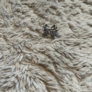 Silverfärgad ring med rosett - Superfin ring i silverfärg med en stor, detaljerad rosett som verkligen sticker ut. Perfekt accessoar för dig som vill ha något unikt och sött på fingret. Ringen har en glansig finish och är formad som en klassisk rosett.