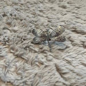 Silverfärgad trollslända ring  - Unik ring i form av en trollslända med detaljerade vingar i silverfärg. Perfekt accessoar för att ge din outfit en cool och personlig touch. Snygg att fästa på jackan, väskan eller tröjan.