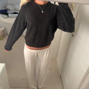 Mörkgrå stickad tröja med rund hals - Mysig mörkgrå stickad tröja med rund hals och långa ärmar. Tröjan har en lite loose passform och ribbade muddar vid ärmslut och nederkant. Perfekt att slänga på sig när det är kyligt ute. Enkel och stilren design som funkar till allt.