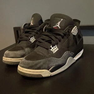 Nike Air Jordan 4 Retro Black canvas - Säljer ett par Nike Air Jordan 4 black canvas i svart med vita och röda detaljer. Skorna har klassisk mesh och mocka, ikonisk Jumpman-logga på plösen och hälen samt snörning. Snygg kontrast mellan svart ovandel och vit sula med röda accenter undertill. Riktigt feta skor.