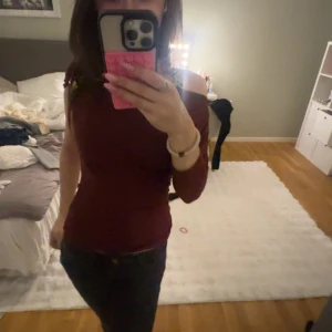 Vinröd offshoulder topp - Säljer en vinröd offshoulder topp med trekvartsärm. Sitter tight och har en snygg, figurnära passform. Perfekt för dig som gillar en enkel men stilren look. Toppen är enfärgad och har en mjuk känsla mot huden.