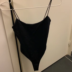 Svart body från Zara  - Snygg svart bikini med smala axelband och enkel, stilren design. Modellen är en one-piece med hög skärning och mjukt tyg som sitter skönt mot kroppen. Perfekt för dig som gillar minimalistisk stil på stranden.