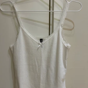 Vit spetskantad linnetopp  från H&M - Supersöt vit linnetopp från H&M Divided med smala axelband och spetskant runt halsringningen.