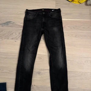 Svarta  jeans från Lee W31 L32 - Säljer ett par svarta jeans från.. Jeansen har klassisk femficksdesign, svarta sömmar och Lee-logga på bakfickan. Materialet är stretchigt denim. Mycket gott skick 