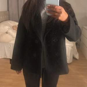 Kappa  - As snygg svart kappa från design by si. Använd några få gånger men ser helt ny ut. Nypris ca 750kr. 