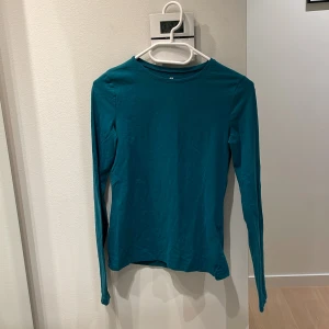 Turkos långärmad tröja | H&M - Enkel och stilren turkos långärmad tröja från H&M. Tröjan har rund halsringning och är tillverkad i mjuk bomull, perfekt för lager-på-lager eller som den är. Passformen är normal och materialet känns skönt mot huden. Storlek: 164
