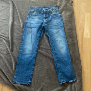 G-Star RAW 3301 Straight jeans blå - Blå jeans från G-Star RAW, modell 3301 Straight. Klassisk femficksdesign med raka ben och snygga slitningar framtill och baktill. Jeansen har orangea kontrastsömmar och normal passform. 