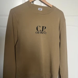 Beige sweatshirt från CP Company - Riktigt snygg beige sweatshirt från C.P Company med svart logotyp tryckt på bröstet. Tröjan är i princip i nyskick. Skriv för fler bilder eller för svar på frågor! 