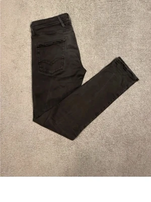 Replay Anbass svarta jeans, storlek 32 - Säljer ett par svarta Replay Anbass jeans i storlek 32. Jeansen har en slim passform, klassiska fem fickor och Replay-logga på fickan fram. Materialet är stretchigt jeans och färgen är snyggt mörk med lätt tvättad look. Perfekta till sneakers eller boots.