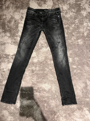 Svarta skinny jeans med slitningar - Säljer ett par svarta skinny jeans med snygga slitningar och tvättade detaljer. Jeansen har klassisk femficksdesign, dragkedjegylf och smal passform hela vägen ner. Perfekta för dig som gillar en tajt look och vill ha ett par stilrena jeans till vardags.