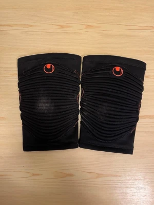 Uhlsport Knäskydd - 2 st knäskydd från Uhlsport använda en gång i fotbollsträning.  Storlek M. Medium: bredden överst 14 cm, bredden nederst 11 cm, längden 24 cm. Kan hämtas i Vallentuna.