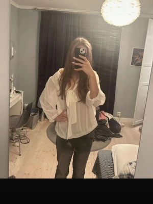 Vit offshoulder blus med rosett - Snygg vit offshoulder blus från 4ice med stor rosett framtill. Blusen har långa ärmar med resår vid ärmslut och nederkant, vilket ger en avslappnad och trendig look. Tillverkad i ett lätt och luftigt material som känns skönt mot huden.