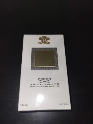 Creed parfym 100 ml  - Exklusiv parfym från Creed i elegant vit kartong med gulddetaljer och klassisk logga. Förpackningen rymmer 100 ml och har en lyxig känsla med stilren design och tydlig märkning. Perfekt för dig som gillar exklusiva dofter och snygg design.