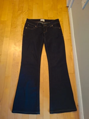 Mörkblå bootcut jeans från Abrand - Snygga mörkblå bootcut jeans från Abrand Jeans med klassisk femficksdesign och kontrastsömmar. Jeansen har låg midja och utsvängda ben, perfekta för en trendig och avslappnad look. Materialet är kraftig denim i bomull.