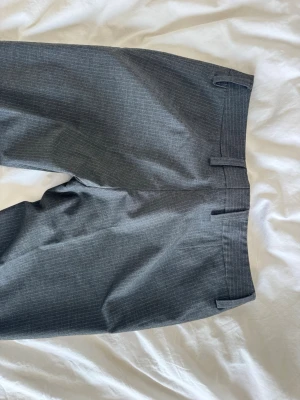 Grå kostymbyxor med diskret mönster - Dags att sälja mina skitnsygga lågmidjade lite baggy kostymbyxor från hm! Köpta second hand men bara använda några fåtal gånger sedan köp och i jättebra skick utan några defekter! Står 40 på lappen men skulle säga att de passar perfekt på någon med strl m eller 36/38! Benen är uppsydda men går lätt att bara sprätta upp utan problem så funkar även någon lite längre än mig! ( är 173 och de går ner till marken på mig!) Tveka inte att fråga eller förslå pris!