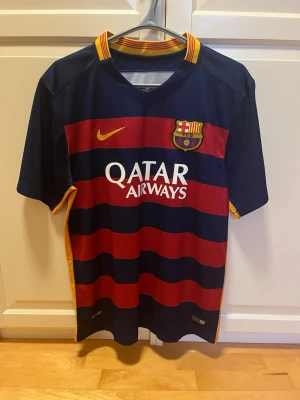 FC Barcelona 15/16 fotbollströja Nike strl XL - FC Barcelona 15/16 matchtröja från Nike i blå och röd med gul tryck. Kortärmad modell i lätt och ventilerande polyester, med flera sponsorloggor och klubbmärke på bröstet. Enbart en defekt där trycket på inne kragen ”mes un que club” har försvunnit i tvätten (se bild).