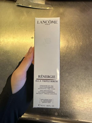 Lancôme Rénergie H.C.F. Triple Serum - Lancôme Rénergie H.C.F. Triple Serum är ett avancerat anti-age serum i en silverfärgad förpackning. Innehåller hyaluronsyra, C-vitamin och niacinamid för att motverka rynkor och mörka fläckar. Förpackningen rymmer 50 ml och har en lyxig, modern design. (OANVÄND i PLAST)