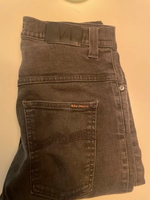 Svarta jeans från Nudie Jeans - Säljer ett par svarta jeans från Nudie Jeans med klassisk femficksmodell och diskret logga på bakfickan. Säljer då dom var för små. 