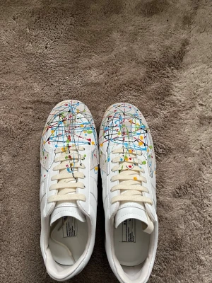 Maison Margiela sneakers - Maison Margiela sneakers i vitt skinn med paint splitter tyvärr finns ingen box tveka inte att skriva om några funderingar 