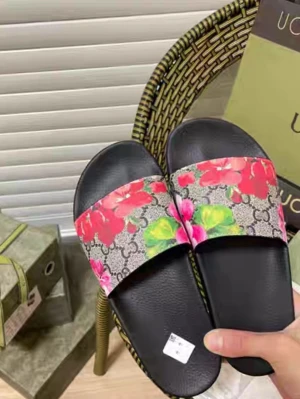 Gucci sandaler med blommigt mönster - Snygga slides från Gucci med svart sula och bred rem i klassiskt GG-mönster. Remmen har färgglada blommor i rosa, rött, blått och grönt. Perfekta för sommaren och ger en lyxig touch till din outfit. Materialet är konstläder och textil.