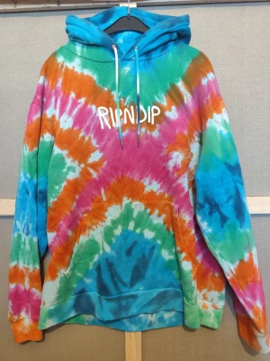 RipNdip tie dye hoodie, Strl M i bra skick - Jag säljer en hoodie från RIPNDIP i tie dye-mönster med loggan tryckt på bröstet. Trycket sticker ut och är 3D mer än man kan tro. Försökte fota så det syns men lyckades inte särskilt bra. Annars klassisk passform med huva och magficka. Tillverkad i bomull och märkt “Designed in California”. Skicket är gott, sparsamt till normalt använd med inget större att anmärka på. titta gärna på mina andra annonser och se om något annat faller dig i smaken.