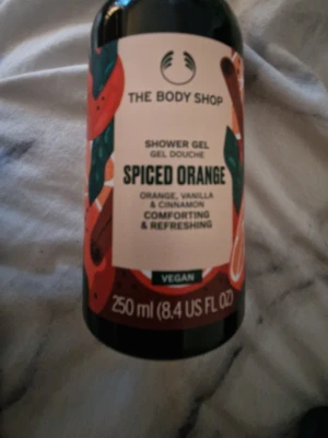 The Body Shop Spiced Orange duschgel - Duschgel från The Body Shop med doft av apelsin, vanilj och kanel. Flaskan rymmer 250 ml och har en färgglad etikett med orangea och gröna detaljer. Vegansk formula som ger en fräsch och uppfriskande känsla.