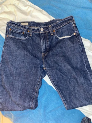 Levi's 512 mörkblå jeans W31 L32 - Säljer ett par klassiska Levi's 512 jeans i mörkblå denim. Modellen har rak passform, fem fickor och snygga kontrastsömmar. Perfekta för dig som gillar tidlös stil och vill ha ett par jeans som funkar till allt. Märke och storlek syns på läderpatchen bak.     Rensar min garderob och vill bara bli av med detta