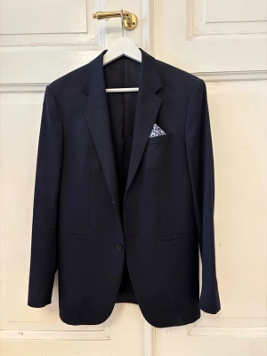 COS KAVAJ NAVY - Säljer denna snygga mörkblåa kavajen från COS, perfekt över en tisha exempelvis! Köpt för ca 2500kr, säljer för 749kr👌Toppen skick, storlek 46. Modellen är ca 185cm.