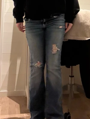 Blå bootcut jeans med slitningar - Ett par blå bootcut jeans med slitningar och hål på låren och knäna. Och med fina fickor där bak